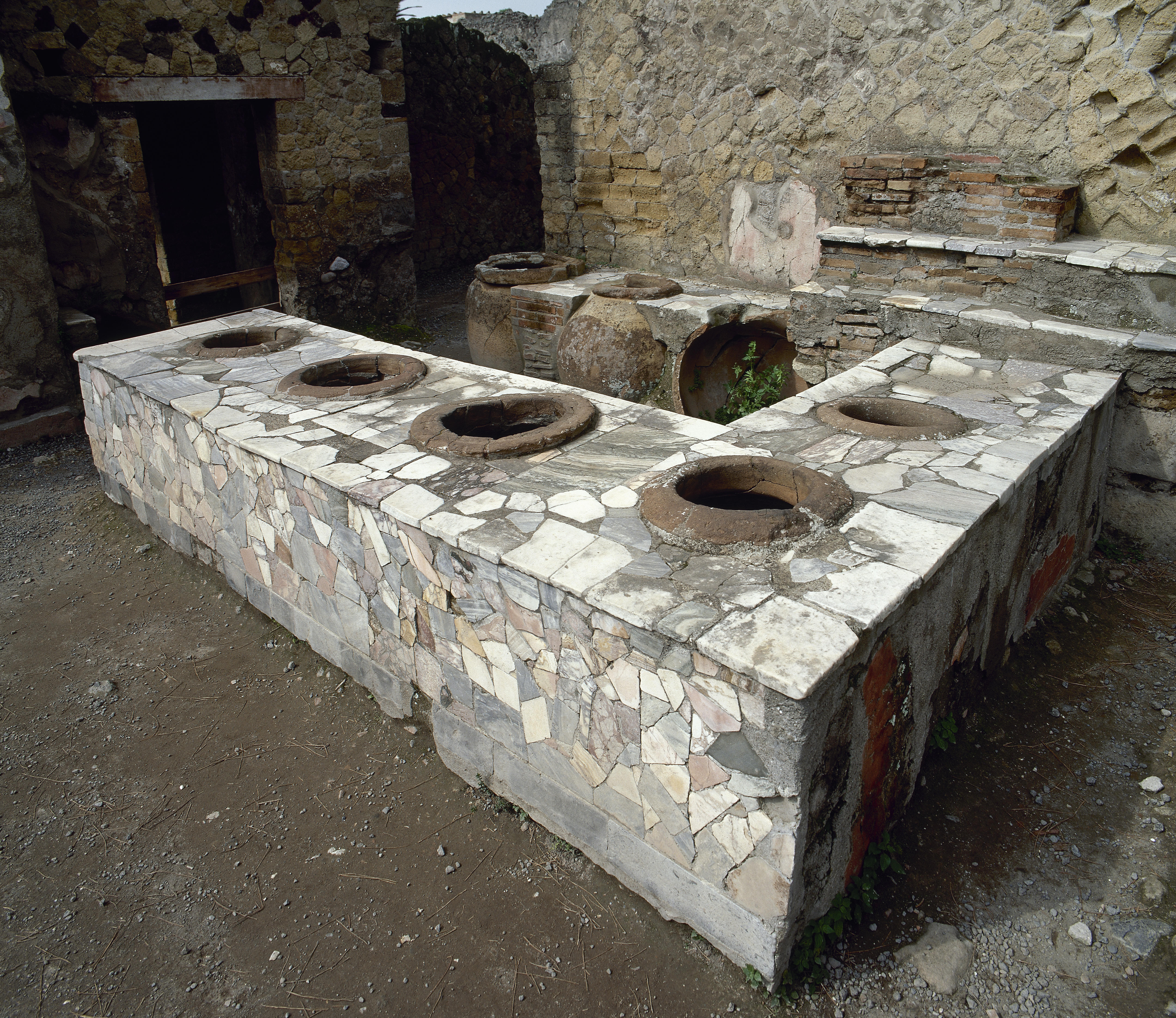 A photograph of the remains of a popina, with vats for food sunk into the bar.